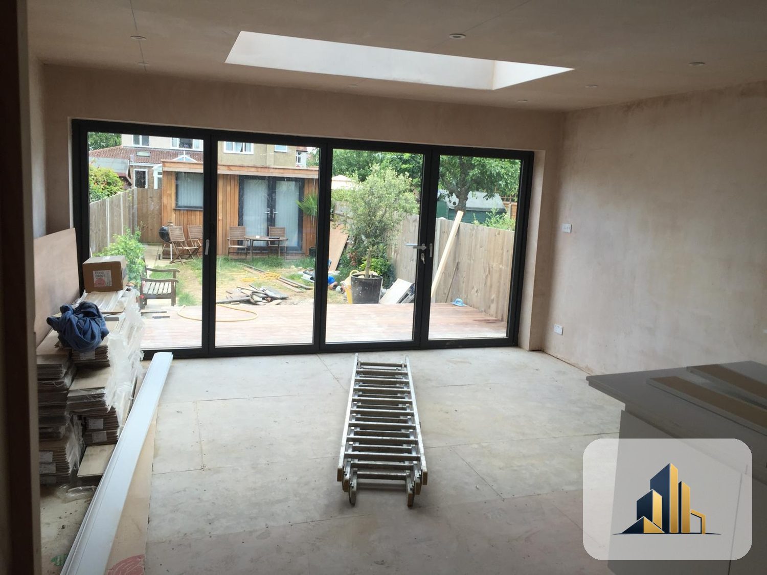 Interior of the Motspur Park extension looking out through new bifold doors to the deck, with a rooflight above