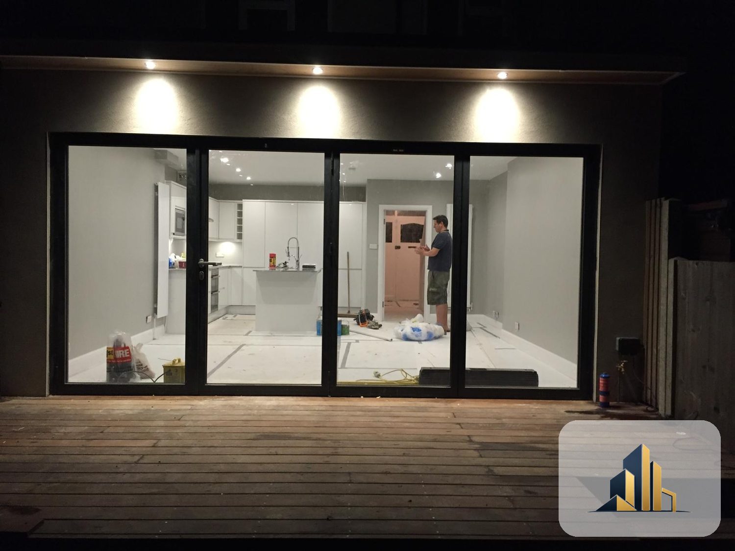 Open-plan kitchen in the Motspur Park extension seen at night through the bifold doors