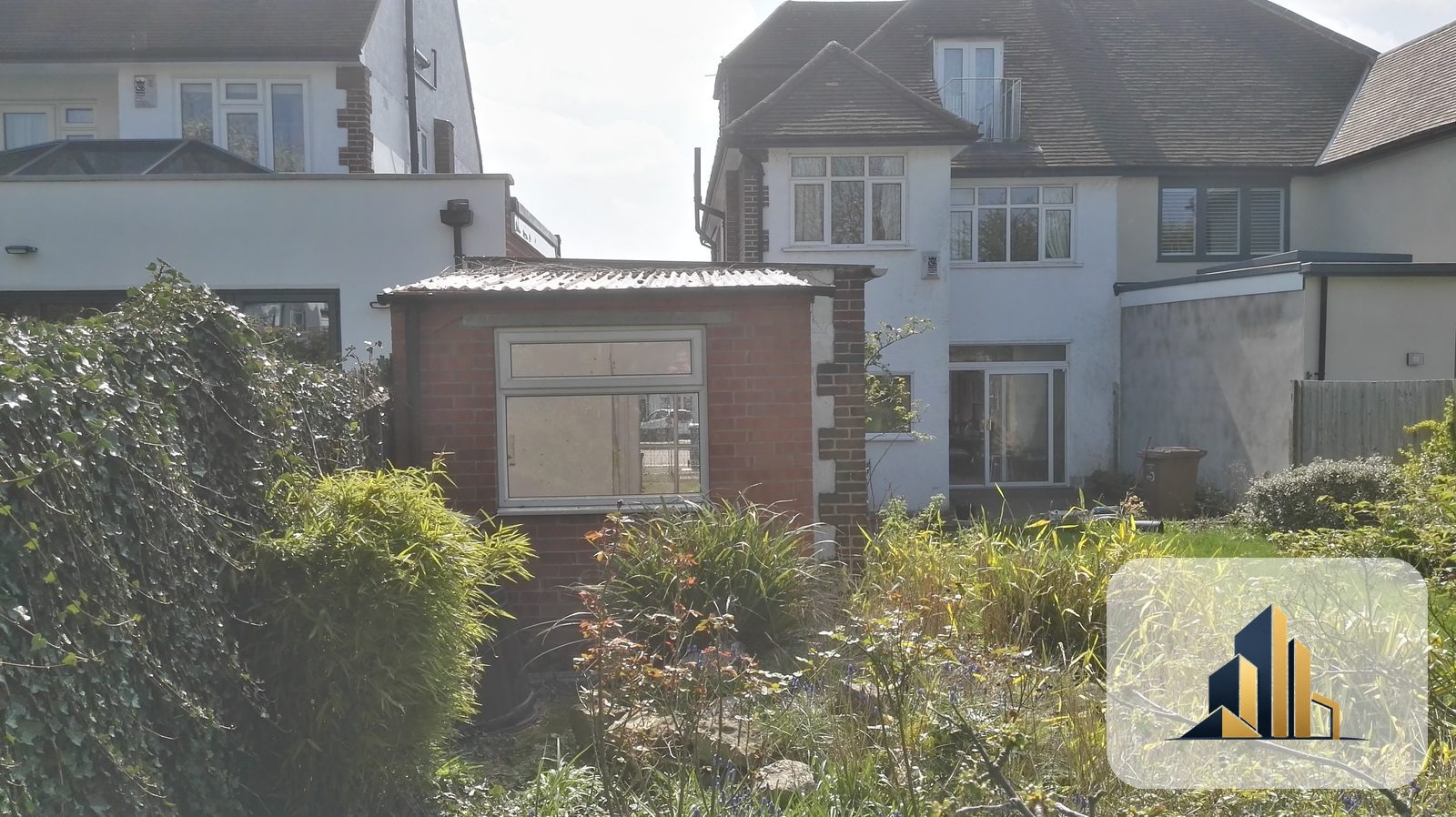 Dated brick garage with an ageing corrugated roof in a Raynes Park garden before the works