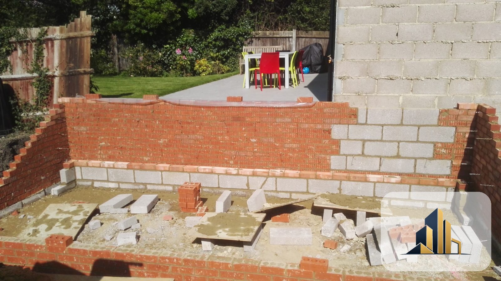 New brick and block cavity walls under construction with the porcelain patio laid behind, Raynes Park