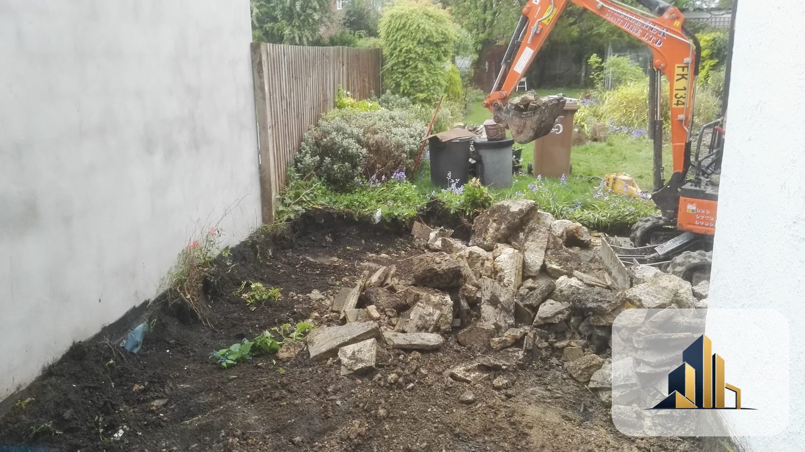 Mini-excavator lifting old slabs and digging out foundations at the rear of a Raynes Park home