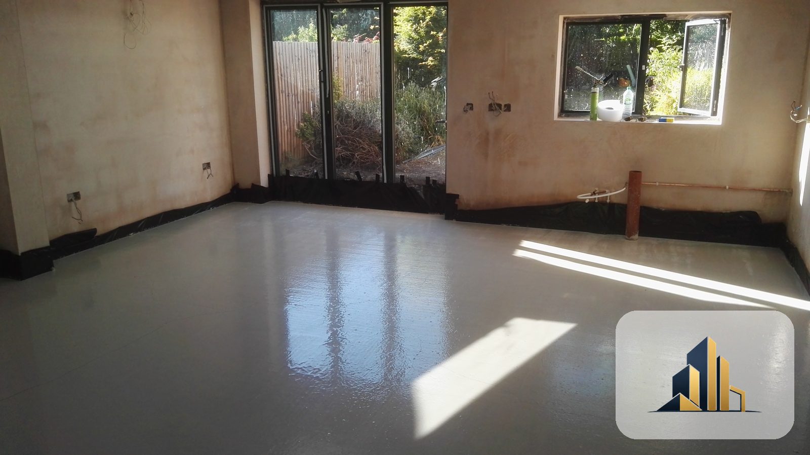 Newly plastered open-plan room with a freshly screeded floor, bifold doors and window installed, Raynes Park